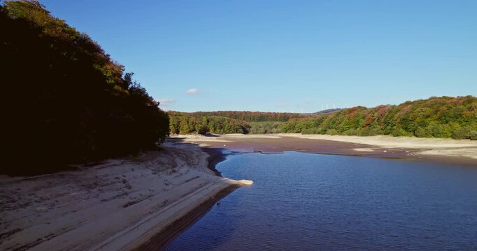 long aerial shot which runs along the edge of an almost empty lake to the arid part