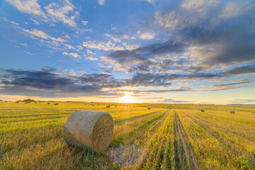 A Beautiful Golden Sunset Cascading Over Rolling Hayfields Under Dramatic Clouds