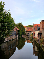 Obraz premium Serene Reflections of Historic Brick Houses on a Quiet Bruges Canal