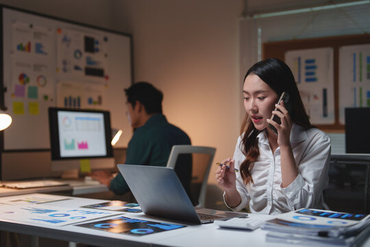 Asian businesswoman working late talking on phone in office