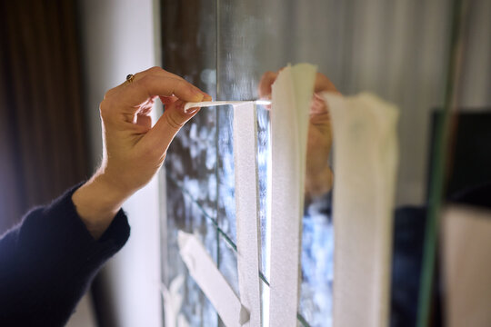 Mirror masking preparation, Detail oriented process of taping mirror for painting, Meticulous handwork involves aligning masking tape precisely on reflective glass surface