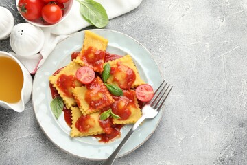 Delicious ravioli with tomato sauce and basil served on grey table, flat lay. Space for text