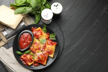 Delicious ravioli with tomato sauce, cheese, grater and basil on grey table, flat lay. Space for text