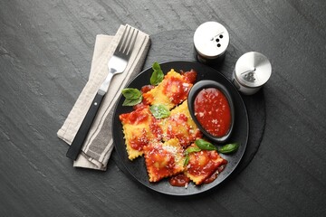 Delicious ravioli with tomato sauce, cheese and basil served on grey table, flat lay