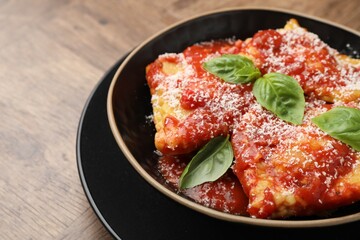 Delicious ravioli with tomato sauce, cheese and basil on wooden table, closeup