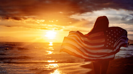 Happy woman holding american USA flag and running on the beach. Independence Day, travel concept