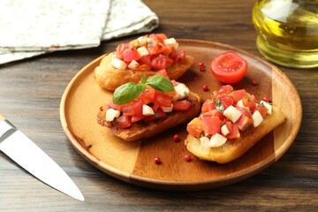 Tasty bruschettas with tomatoes, mozzarella cheese and basil served on wooden table, closeup