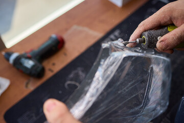 Polishing cloudy headlight using sanding sponge and rotary tools, Mechanic carefully restoring vehicle headlight with polishing compound and rotary device in workshop