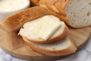 Slices of baguette with butter on white marble table, closeup