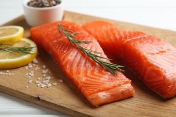 Pieces of salmon fillet, spices and lemon on white wooden table, closeup