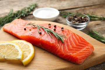 Piece of salmon fillet, spices and lemon on wooden table, closeup