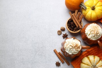 Tasty pumpkin latte with whipped cream in cups, spices and ingredients on light grey table, flat...