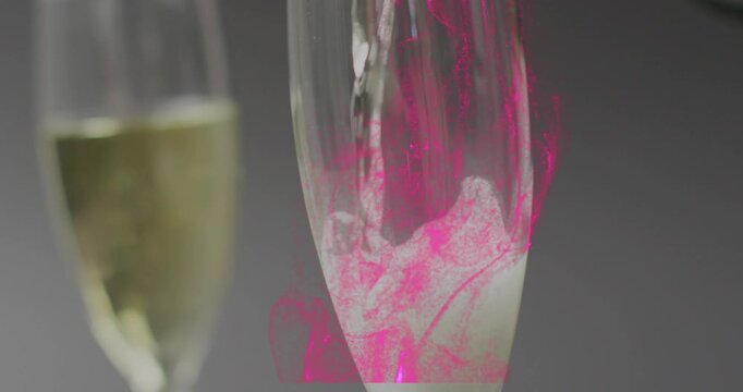 Pink droplet falling from top starting bottle pouring, tall flute filling and making frothy swirls