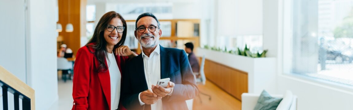 Smiling senior management team posing together in a modern office environment