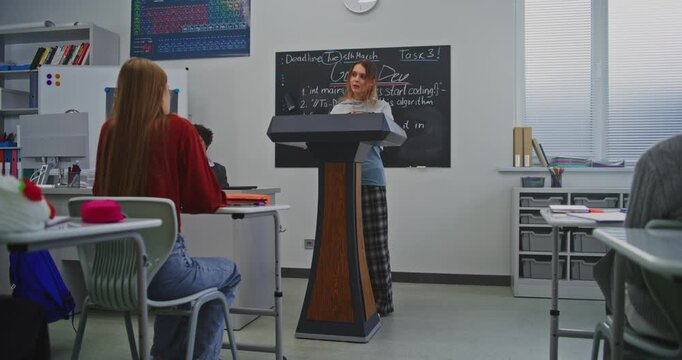Young Woman Speaks Confidently at Podium, Smiling While Addressing Classmates and Teacher. Concept of Leadership, Confidence, and Growth of Communication Skills Through Modern Education. Dolly Shot.