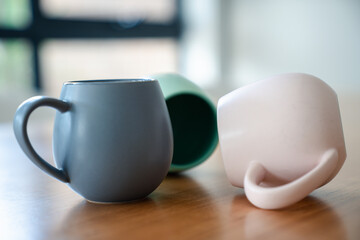 Colorful  stackable ceramic mugs  on wooden table in soft minimal style.