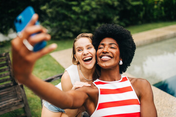 Two friends take a joyful selfie by the poolside