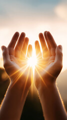 Two raised hands capture warm sunlight shining through in a serene outdoor setting.
