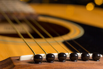 the guitar is acoustic. strings and saddle on a blurred background, close-up.