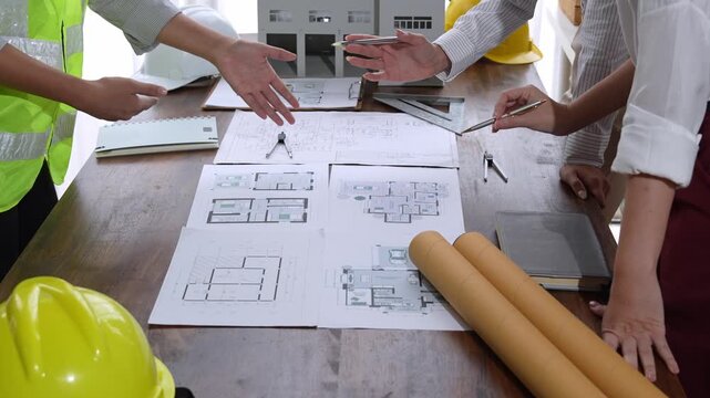 Architects and engineers reviewing building blueprints and model