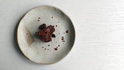 Remains of some chocolate chip cookies on small plate. Handmade rustic ceramic saucer with crumbs...