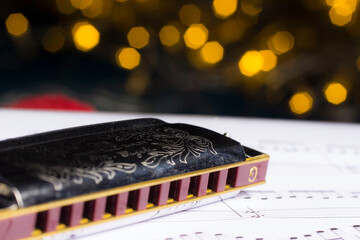 harmonica, music book on a blurred background with highlights. bokeh, close-up.