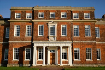 Fototapeta premium Grand georgian mansion with white columns and red brick facade