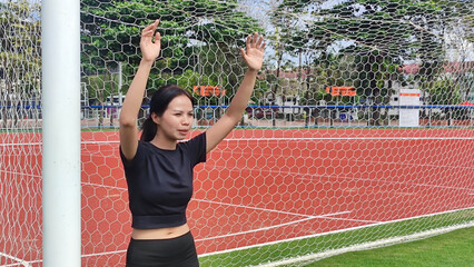 Soccer Goal Keeper in Action: A determined soccer goal keeper stands confidently in front of the goal, her arms raised in anticipation. The image captures the focus, athleticism.