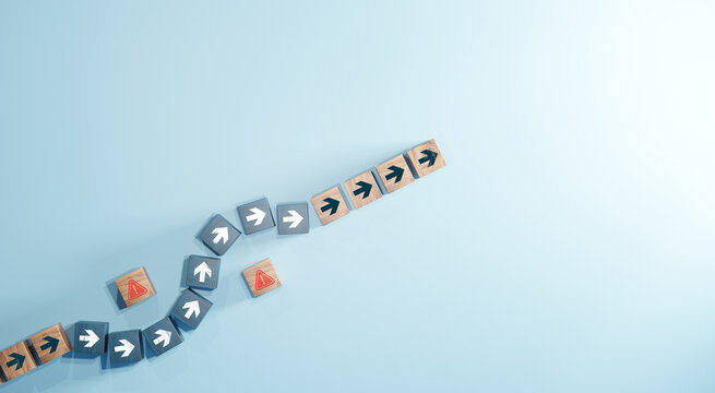 Wooden blocks with arrow icons changing direction to avoid red warning symbol on blue background. Concept of business strategy, decision making, and problem solving.