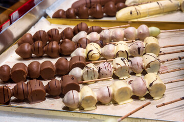 Closeup of a chocolate coated fruit skewers. Rows of chocolate dipped apple, banana strawberry skewers lined up at a Christmas market stall. Schokofrucht - Traditional German holiday treat