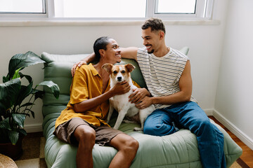 Young gay couple relaxing with their pet dog on a cozy sofa at home