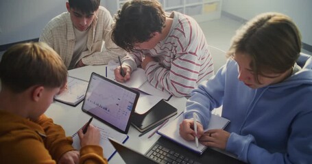 Small Group of Teenagers Engaged in Digital Learning Task, Centered Around Tablet Displaying Financial Charts or Graphs. Concept of Integration of Technology, Data Analysis and Visual Learning. - Powered by Adobe