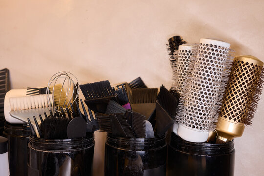 Varied brushes catching studio glow, Colorful tools reflect warm lighting effects, Stylist prepares styling tools with textured bristles under bright studio illumination