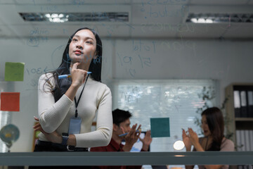 Asian businesswoman brainstorming ideas on glass board