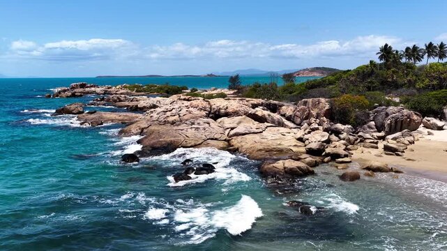 Beautiful aerial footage showcasing the turquoise waters and rocky shoreline of Rose Bay in Bowen. Clear shallows reveal reef textures as the camera glides along the coast, capturing the colours.