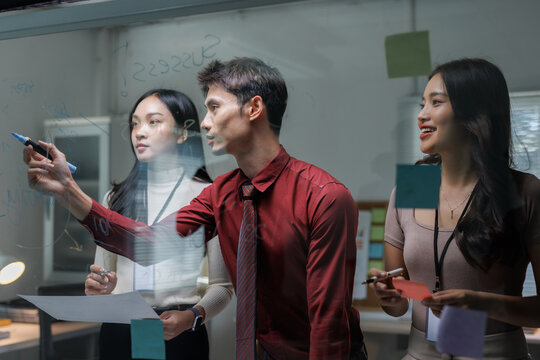 Business team collaborating brainstorming ideas on glass board