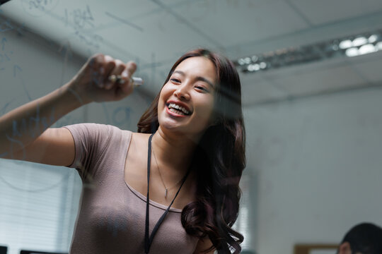 Young businesswoman writing ideas on glass board