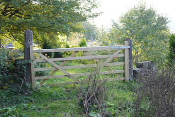New Wooden Gate And Stone Posts In A Sunlit Rural Landscape At Black Rocks, Cromford, Derbyshire, Surrounded By Lush Green Foliage And Trees.