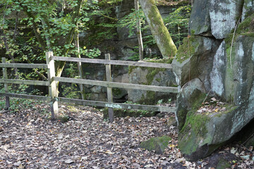 Weathered Wooden Fence With Fallen Autumn Leaves And Moss-covered Rocks In The Ancient Woodland Of Black Rocks, Cromford, Derbyshire