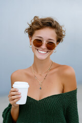 Happy woman holding coffee cup smiling outdoors