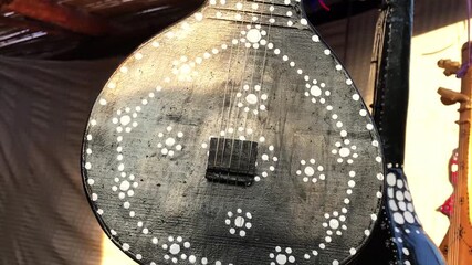 Close-up video of a traditional handcrafted string instrument featuring Sindhi-style white dot decoration on a black wooden body. Ideal for projects related to folk music, cultural heritage, handicraf