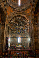 The inside of a Armenian Hovhannavank monastery church with a large chandelier hanging from the ceiling