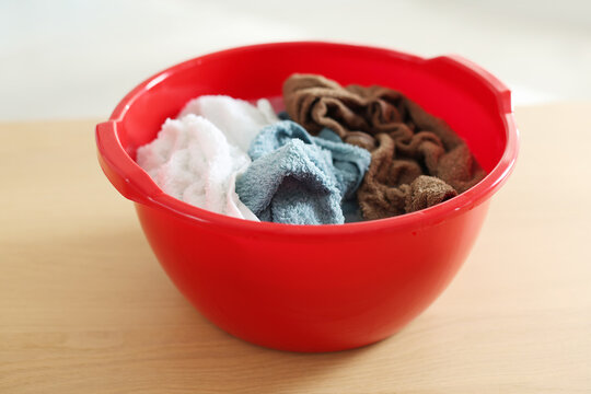 Plastic basin with towels on wooden table indoors, closeup