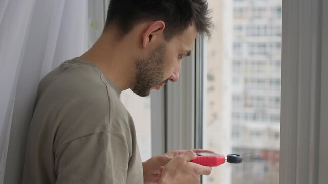 Individual checks natural light intensity near residential window for comfort, Person employs light meter to determine sunlight levels inside apartment for workspace suitability