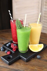 Different tasty smoothies in glasses and ingredients on wooden table, closeup