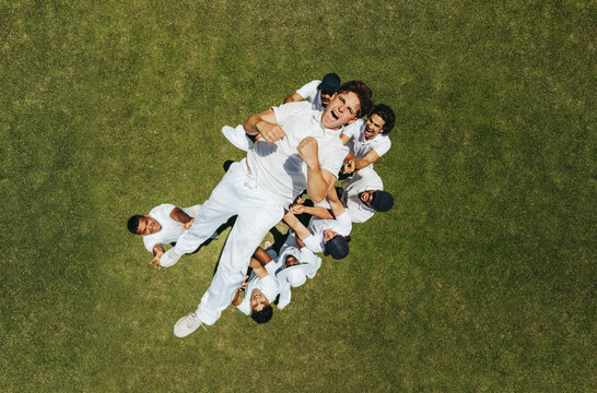 Group of teammates lifting a player in celebration on a grass field