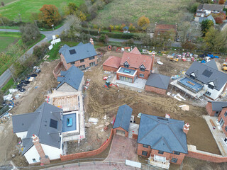 Drone inspection view of a large, near completed family home seen with a newly fitted glass lantern on the conservatory roof. Seen at a British housing development site.