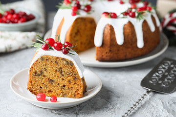 Piece of delicious Christmas cake with icing, cranberries and rosemary on light grey textured table, closeup
