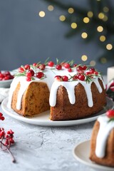 Delicious cut Christmas cake with icing, cranberries and rosemary on grey textured table against blurred lights, closeup. Bokeh effect