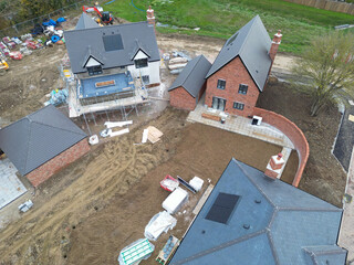Drone view of a near completed detached family home in rural Britain. The back garden has had top soil laid, ready for grass seeding.